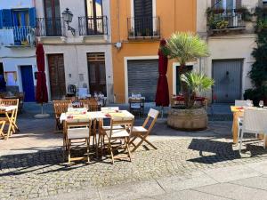 um pátio exterior com mesas, cadeiras e guarda-sóis em La casa di Ale nel centro storico di Cagliari em Cagliari