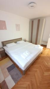 a large white bed in a room with a wooden floor at Apartman 8 in Vrdnik