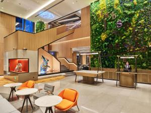 a large green wall in a lobby with tables and chairs at Artyzen Habitat Qiantan Shanghai in Shanghai