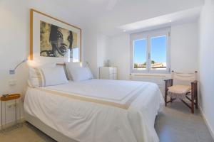 une chambre avec un grand lit blanc avec un tableau sur le mur dans l'établissement CANAMI... Luxury apartment with best sea views., à Colonia Sant Jordi