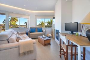 a living room with a couch and a table with a television at CANAMI... Luxury apartment with best sea views. in Colonia Sant Jordi