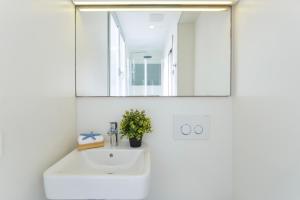une salle de bains avec un lavabo blanc et un miroir dans l'établissement CANAMI... Luxury apartment with best sea views., à Colonia Sant Jordi 21 autres photos
