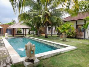 a swimming pool with a statue in front of a house at Kuta Paradise in Kuta Lombok