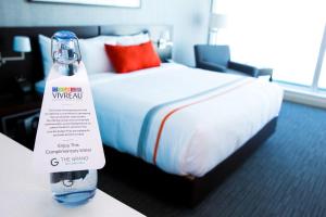 a bottle of water sitting on a table next to a bed at The Grand Winnipeg Airport Hotel by Lakeview in Winnipeg