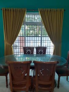 comedor con mesa, sillas y ventana en Homestay Chik Da en Alor Setar