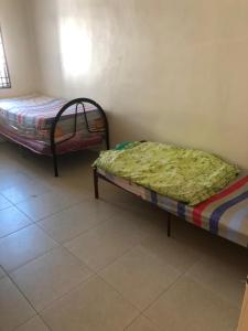 - une chambre avec 2 lits dans une chambre revêtue de carrelage dans l'établissement Homestay Chik Da, à Alor Setar