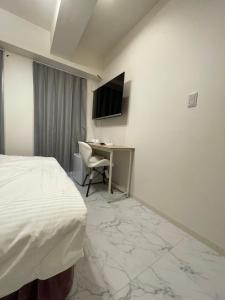una camera d'albergo con letto, scrivania e TV di HotelHarmony日暮里ホテルハーモニー a Tokyo