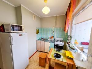 a small kitchen with a refrigerator and a table at Apartment on Prospect Octyabrya in Gomel