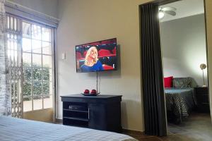 Cozy Hatfield Condo في بريتوريا: غرفة نوم بسرير وتلفزيون على الحائط