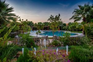 una piscina en un complejo con palmeras y flores en فندق لاجونا ڤيستا بريدة en Buraidah