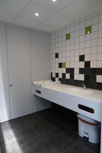 La salle de bains est pourvue d'un lavabo et d'un mur carrelé. dans l'établissement Camping Houtum, à Kasterlee