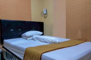 1 dormitorio con 1 cama con sábanas y almohadas blancas en Hotel Fikry Toli Toli, en Tolitoli