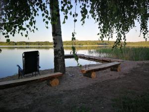 una silla sentada bajo un árbol junto a un lago en Silent Hill in Probark, en Mrągowo