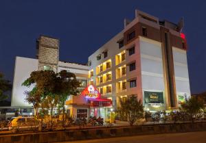 a building with a neon sign in front of it at Hotel Vrishali Executive in Kolhapur