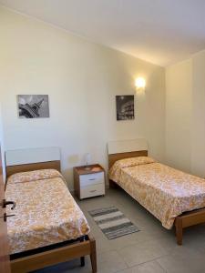 a bedroom with two beds and a table and two pictures at Appartamenti Santa Domenica in Santa Domenica