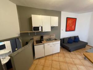 een kleine keuken en een woonkamer met een bank bij L’Appart’ de Spa in Spa