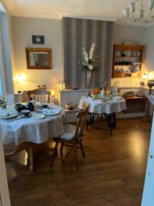 a dining room with two tables with white tablecloths at Southend Airport Bed & Breakfast in Rochford