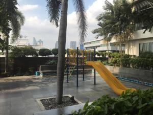 une aire de jeux avec un toboggan jaune à côté d'un palmier dans l'établissement Harmony family room, à Bangkok
