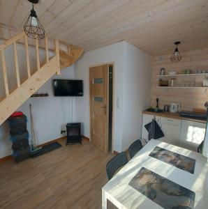 ein Wohnzimmer mit einem Tisch und einer Treppe in der Unterkunft Domek Zacisze Gór Słonnych in Tyrawa Wołoska