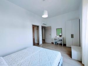 Habitación blanca con cama y escritorio en Sa Banita affittacamere, en Bauladu
