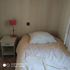 a small bedroom with a white bed and a nightstand at La maison des loirs in Valréas +2 photos