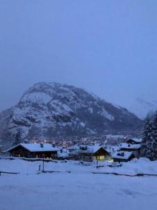 a snow covered mountain in front of a town with houses at Casa Dolonne - A un passo dallo sci in Courmayeur