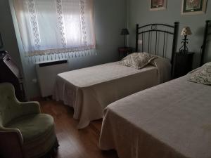 Un dormitorio con dos camas y una silla y una ventana. en Ático en pleno centro de Baiona con garaje, en Baiona