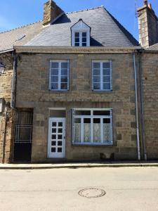 een stenen huis met een witte deur en ramen bij Le gite du Mont in Val Couesnon