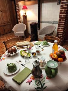 einen Tisch mit einem weißen Tischtuch mit Essen drauf in der Unterkunft LE JARDIN DU ROSSIGNOL in Willeman