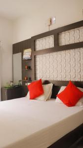 1 dormitorio con cama blanca y almohadas rojas en Sharma Residency Madurai, en Madurai