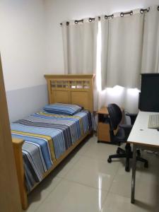 1 dormitorio con cama, escritorio y ordenador en Apto inteiro Seguro e Confortável com piscina, en Anápolis