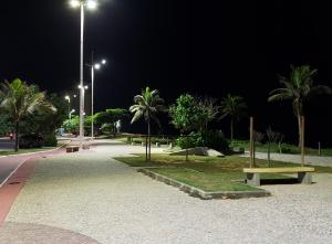 einen Park mit Bänken und Palmen in der Nacht in der Unterkunft Apto Jacaraipe - quadra praia - excelente in Jacaraípe