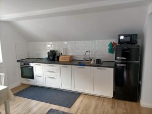 kuchnia z białymi szafkami i czarną lodówką w obiekcie Center House w mieście Ramingstein