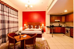 a bedroom with a bed and a table and a kitchen at Icon Hotel Apartments in Dubai