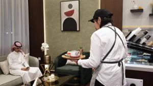 um homem segurando um prato de comida em um quarto de hotel em المنار للوحدات الفندقية em Jeddah