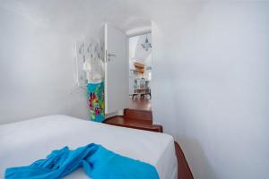a bedroom with white walls and a bed with blue sheets at Kastro Cave House in Pirgos