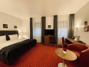 een hotelkamer met een bed, een stoel en een tafel bij Schloss Hotel Herborn in Herborn