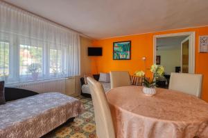 a room with a table and a bedroom with orange walls at Vincze Villa Vendégház in Bükkszék