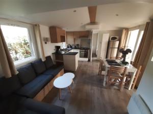 a living room with a couch and a table and a kitchen at Mobil home 6 pers climatisé in Les Mathes