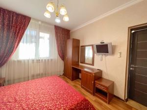 アドレルにあるГостевой дом Альбина 4のベッドルーム(赤いベッド1台、デスク、テレビ付)