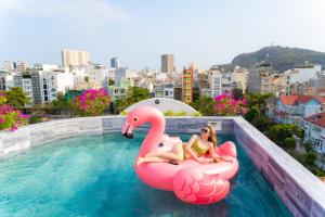 Duas raparigas estão sentadas num flamingo insuflável numa piscina. em La Casa Boutique Hotel em Vung Tau