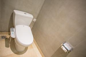 a white toilet in a bathroom with a roll of toilet paper at Grand Sehati & Spa, Ubud in Ubud