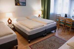 sypialnia z 2 łóżkami, stołem i krzesłami w obiekcie Pension Hotel Mariahilf w Wiedniu