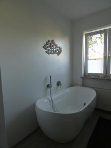 baño con bañera blanca y ventana en Gartenwohnung JULIANA Gstadt LÄUFERs CHIEMSEE HOLIDAY HOME en Gstadt am Chiemsee