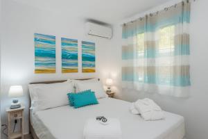 a white bedroom with two beds and two windows at Waves Apartments Melody Glyfada in Glyfada