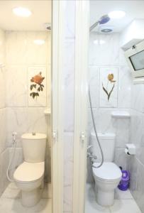 a white bathroom with a toilet and a shower at Hostel Sunset Down town in Cairo