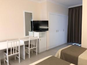 プラヤ・デアロにあるHotel Claramarのデスク、テレビ、ベッドが備わるホテルルームです。