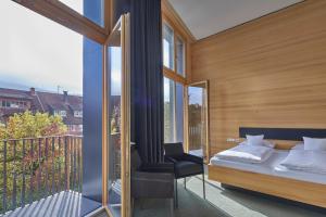 1 dormitorio con 1 cama y 1 silla en el balcón en ElzLand Hotel 9 Linden "Ferienwohnung", en Elzach