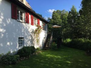 a white house with red shuttered windows and a staircase at Haus Nagel in Hinterzarten