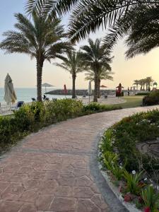 a walkway next to the beach with palm trees at Breathtaking Studio Apartment in Marjan Island in Ras al Khaimah